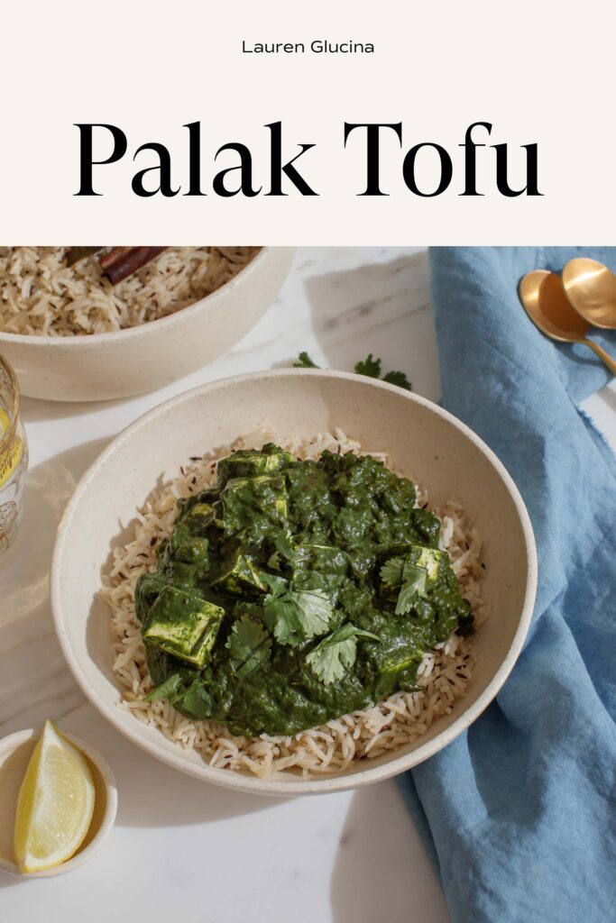 A bowl of spinach and tofu curry on a marble surface with text over the top of the image that simply reads 'Palak Tofu'.