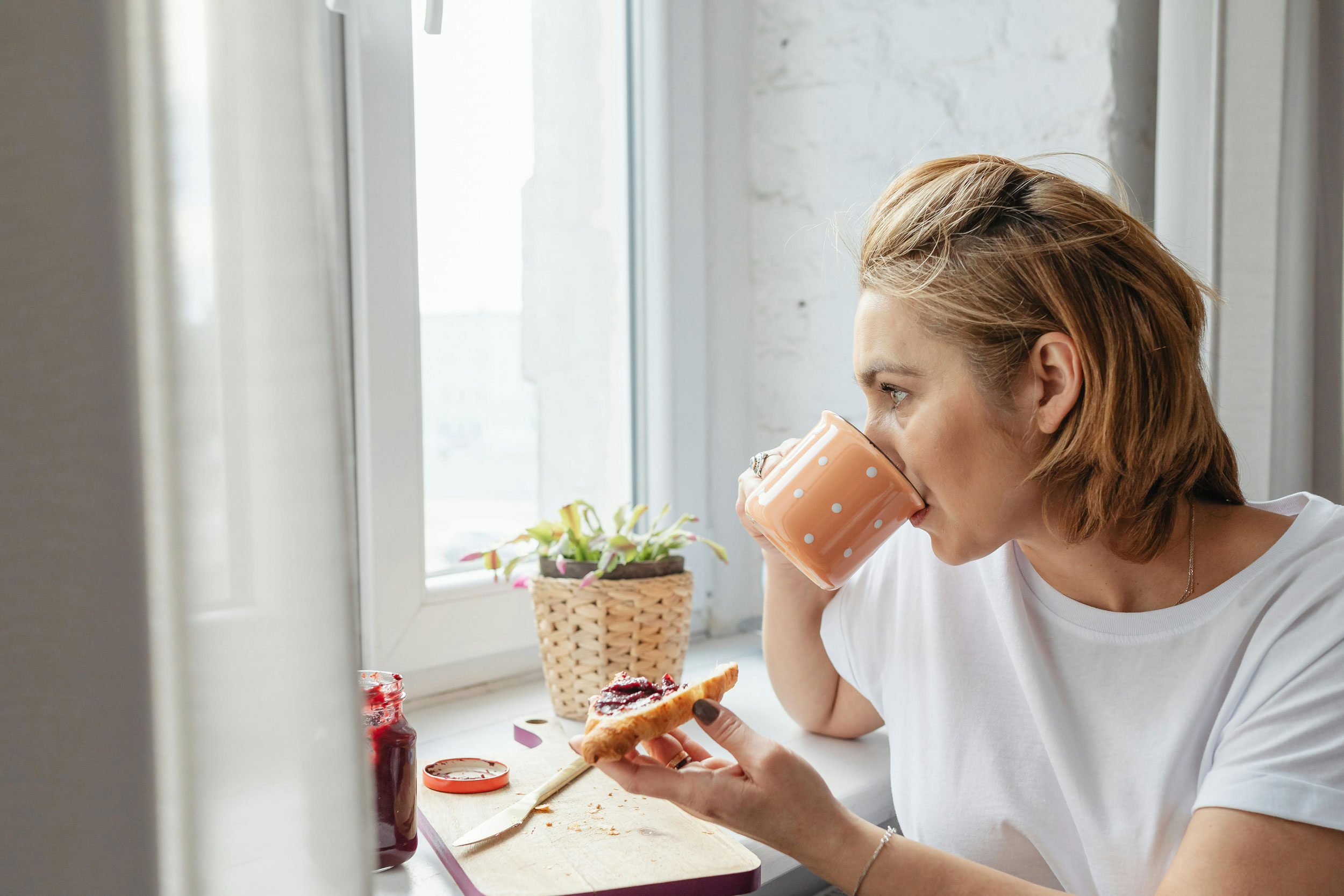 Woman enjoying a croissant with jam for breakfast.