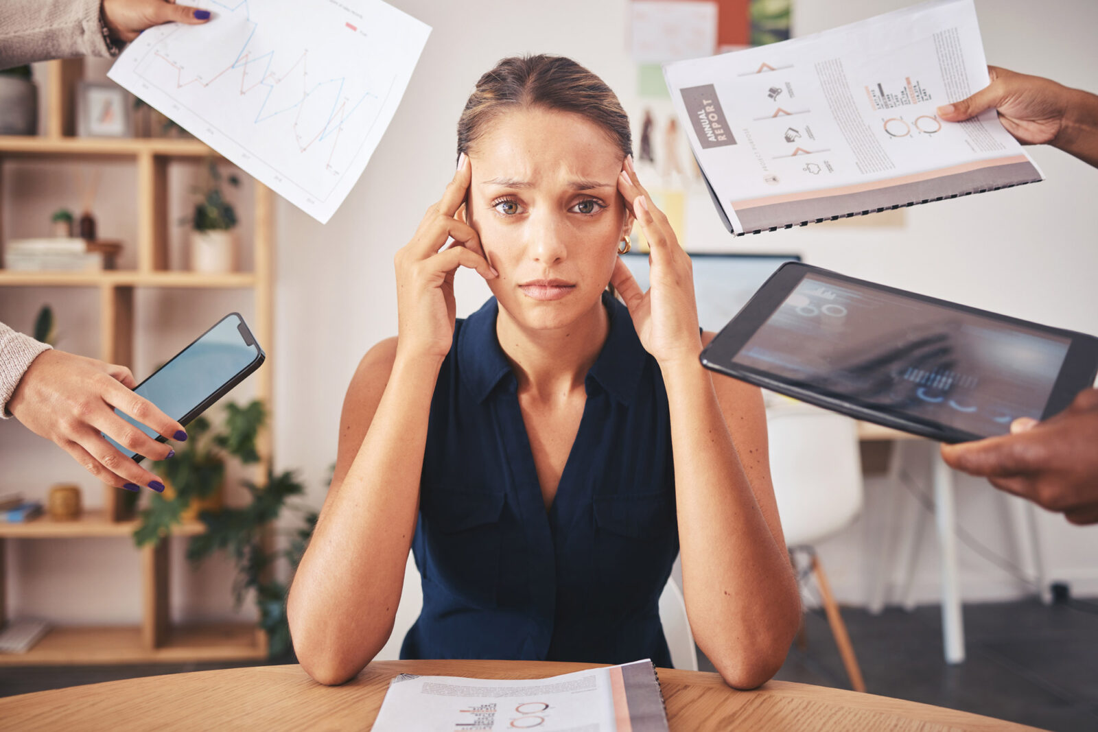A professional woman is overwhelmed at her desk; she doesn't know how to say "No".